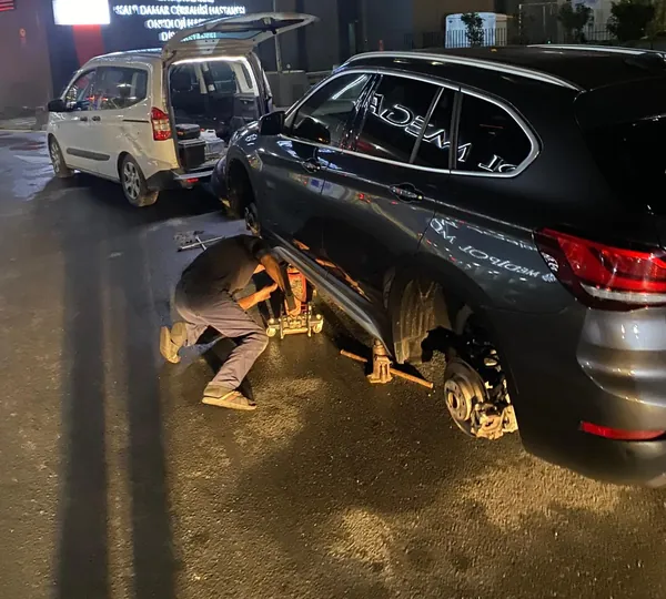 Gece sokakta aracın lastiğini değiştiren mobil lastikçi ustası