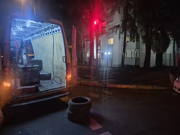Gece yol kenarında kapıları açık mobil servis aracı ve sökülmüş lastikler